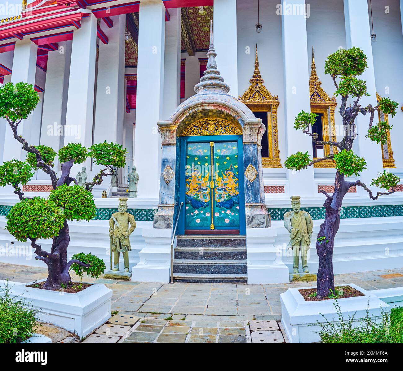 Die farbenfrohe Seitentür zu Ubosot von Wat Suthat mit zwei Wächtern, Bangkok, Thailand Stockfoto