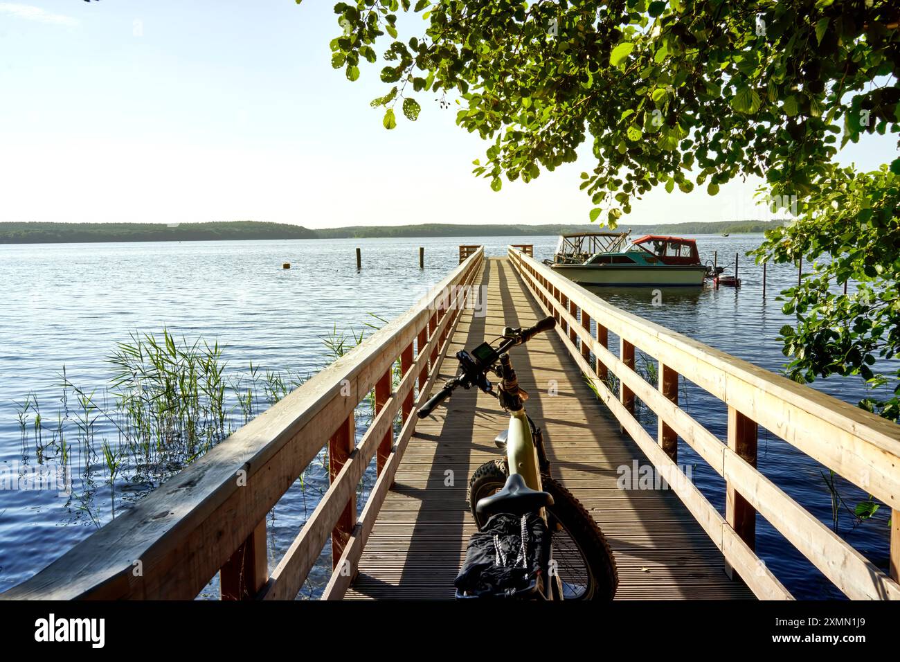 Zentrale Perspektive auf einen Holzsteg in einen See mit Fahrrad, Radtour in Deutschland Stockfoto