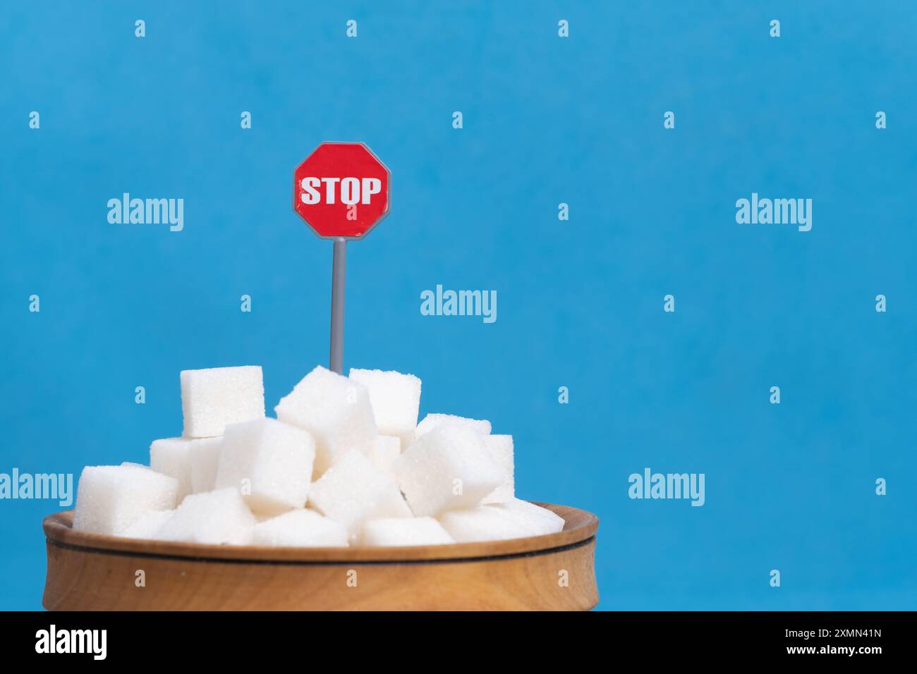 Zuckerwürfel mit rotem Stoppschild auf blauem Hintergrund, Zuckersucht-Konzept Stockfoto