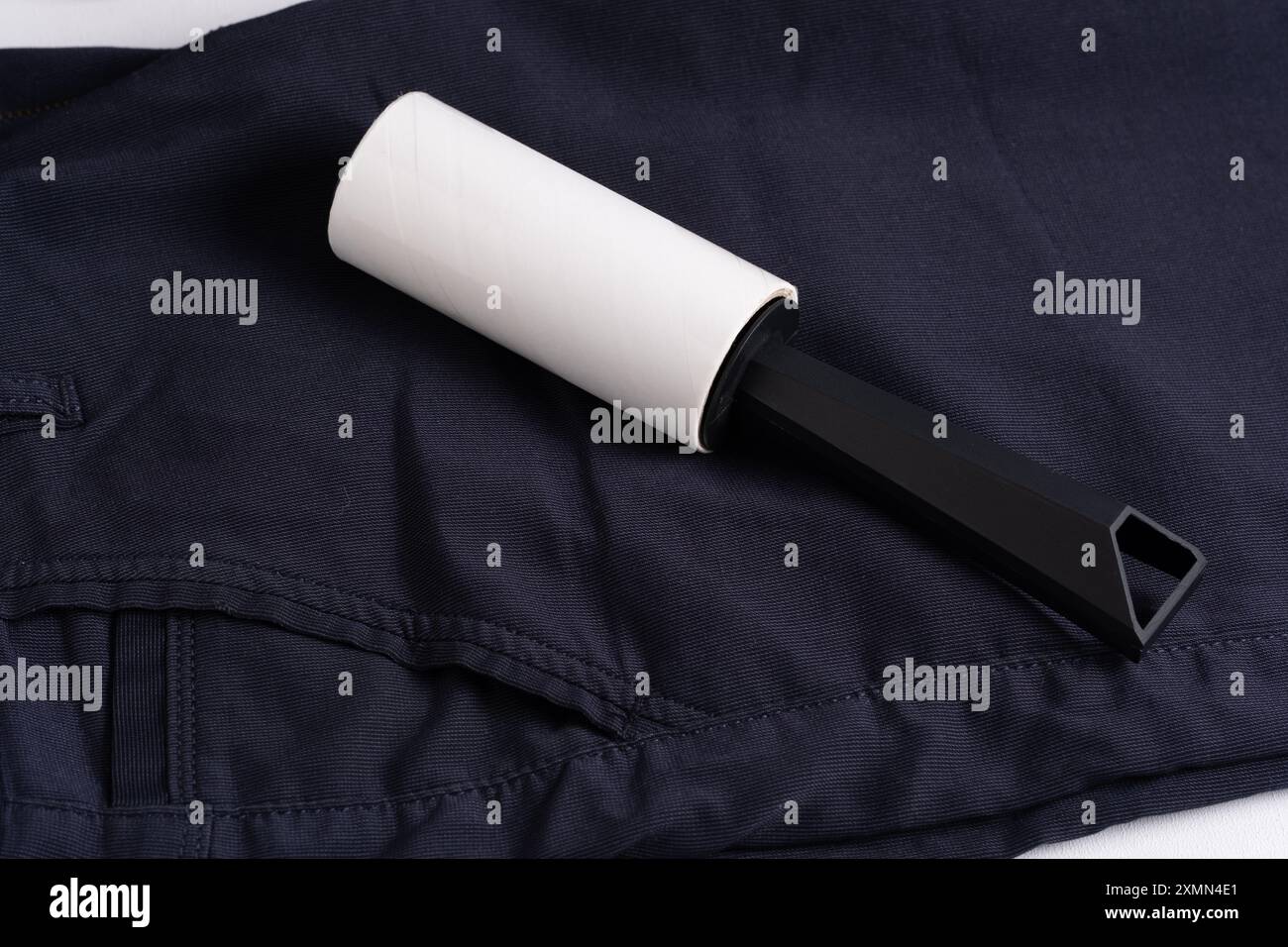 Rolle mit Klebeband zum Reinigen von Kleidung. Auf dunklem Hintergrund der Hose Stockfoto