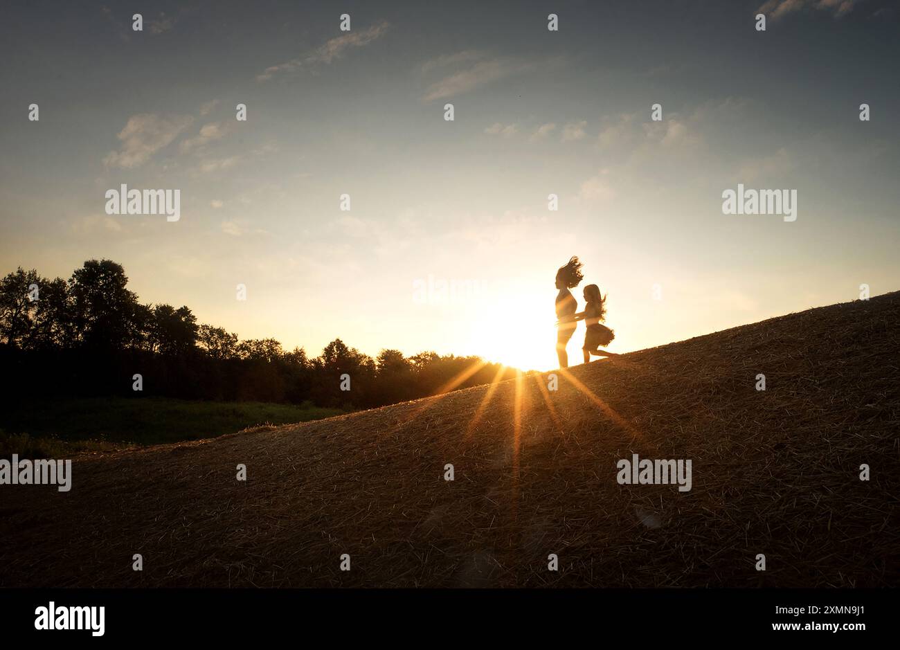 Junge Schwestern, die durch den Sonnenaufgang den Berg hinunter laufen Stockfoto