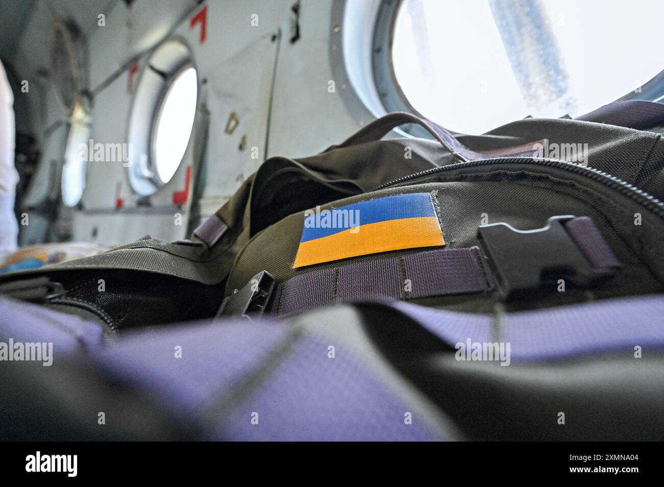 UKRAINE - 11. JULI 2024 - Ein ukrainisches Flaggenpflaster ziert den Rucksack eines der Besatzungsmitglieder eines Mi-8MSB-V Sturmtransporthubschraubers der 16. Brody Separate Army Aviation Brigade. Stockfoto