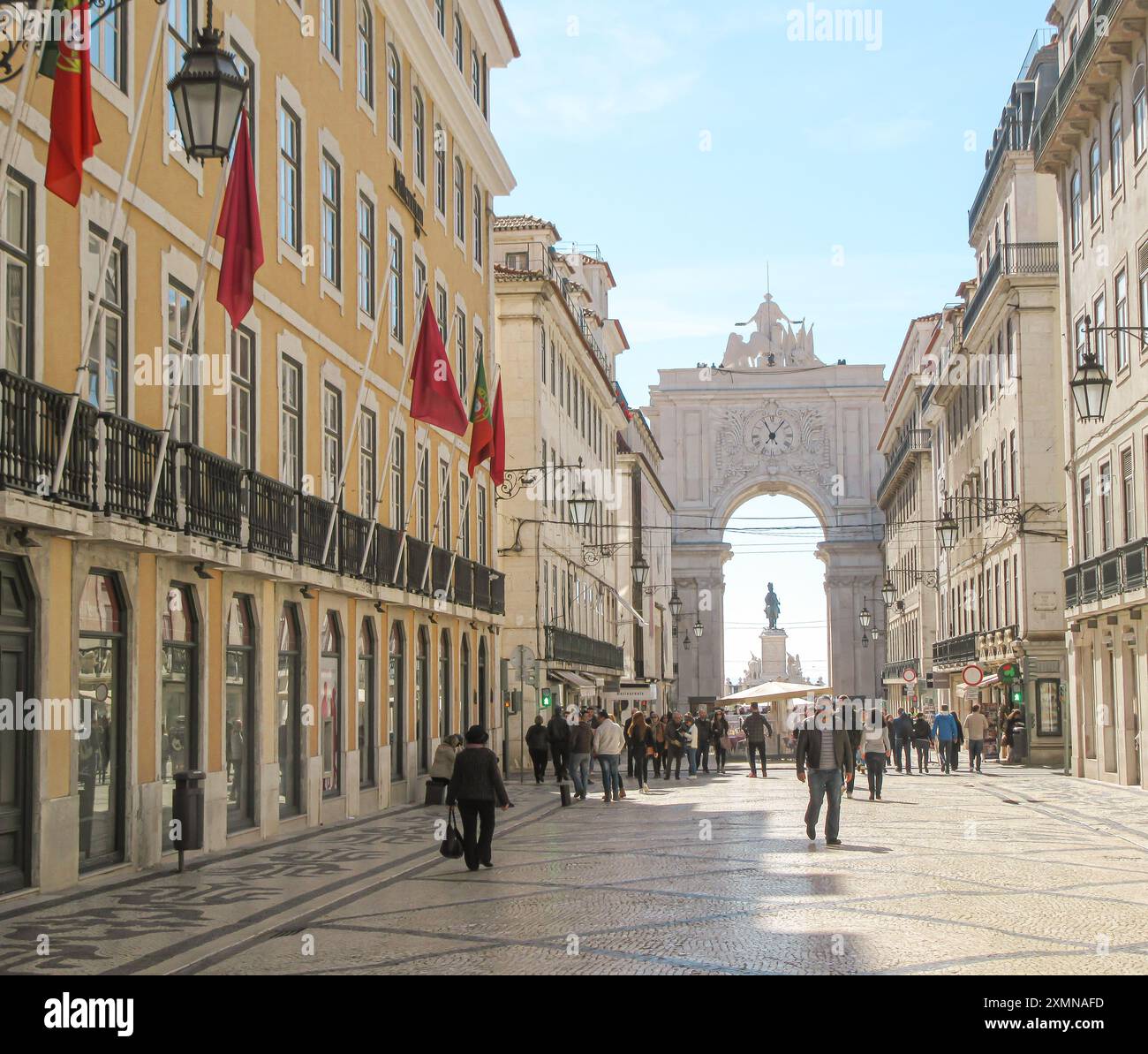 Europäische Straße mit Fahnen, Bogengang und Menschen, die an einem sonnigen Tag spazieren gehen Stockfoto