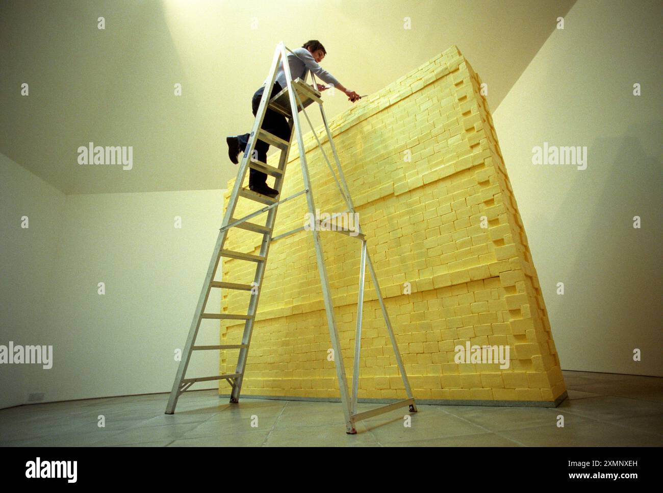 Butter Wall SculptureCrazy Lotterie finanziertes Kunstprojekt einer drei Viertel Tonnen schweren Mauer aus Butter die mazedonische Bildhauerin Elpida Hadzi Vasileva verleiht ihrem 3 720 Block drei Viertel Tonnen Butter Wall, die in der ArtSway Galerie in Sway im Neuen Wald gebaut wurde, den letzten Schliff es hat fünfeinhalb Tage gebraucht, um zu bauen, was Teil ihrer Einfrauenshow ist, wer bin ich? Elpida war im Sommer 1999 Artist-in-Residence im Rahmen des A4E-Programms „The World of Our Landscape“ von ArtSway, das von der National Lottery durch den Arts Council of England finanziert wurde. Bild von Roger Bamber 1999 Stockfoto