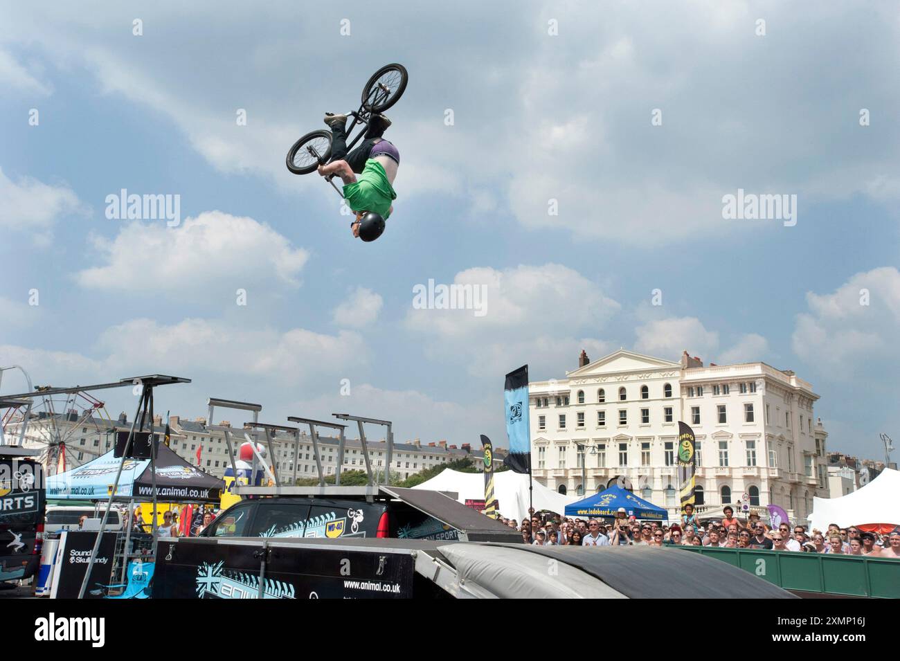 Bild von Roger Bamber : 07 Juli 2013 : Trials Rider James Jones fliegt auf seinem BMX-Fahrrad kopfüber über den Menschenmassen bei der Animal Action Sports Veranstaltung auf der Hove Promenade im Rahmen des Paddle Round the Pier Events am Hove Beach. Die Gebäude in Adelaide Crescent befinden sich dahinter. Stockfoto