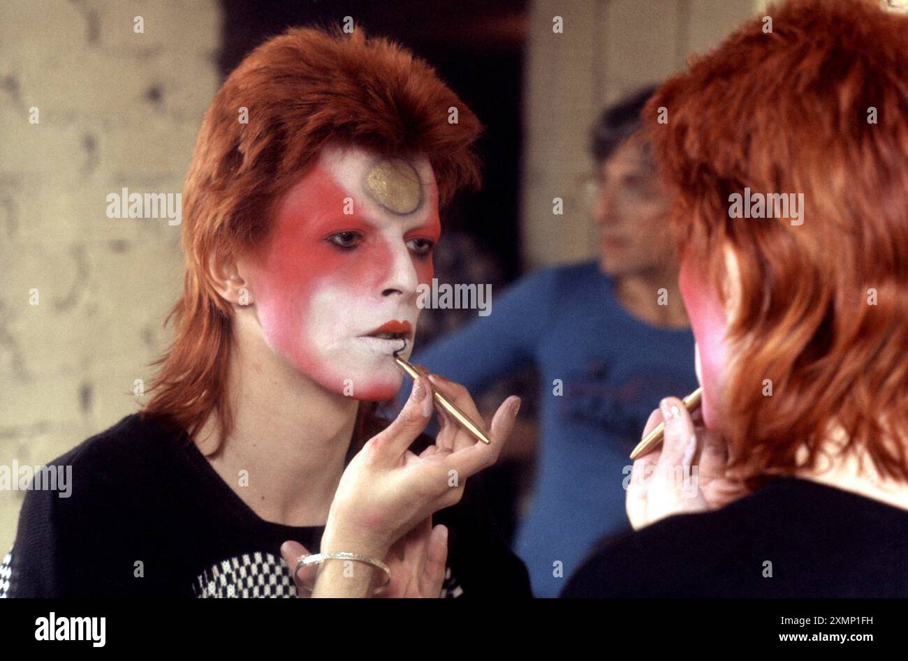 David Bowie, Mai 1973, Make-up, London, Backstage mit Mick Ronson reflektiert hinter ihm. Stockfoto