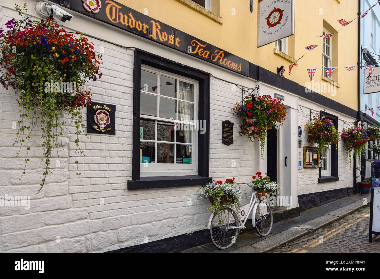 Farbenfrohe, hängende Körbe mit Blumen vor den Teestuben der Tudor Rose im Barbican, Plymouth, Devon Stockfoto