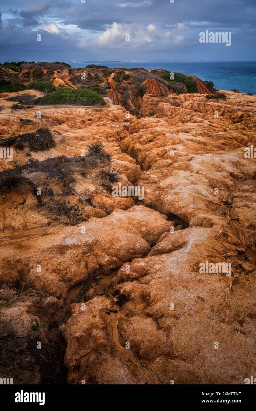 Algarve Küstenlandschaft mit Rissen im Boden vom fließenden Wasser in Richtung Ozean in Lagos, Süd-Portugal. Stockfoto