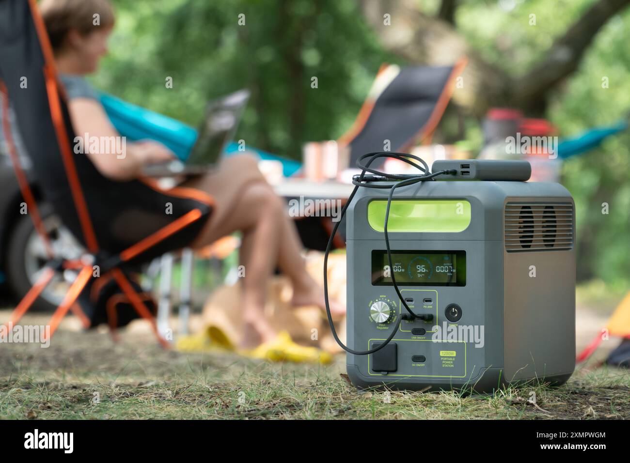 Tragbares Kraftwerk mit Lithium-Ferrophosphat-Batterie, das elektronische Geräte auflädt, die auf einem wilden Campingplatz verwendet werden. Stockfoto