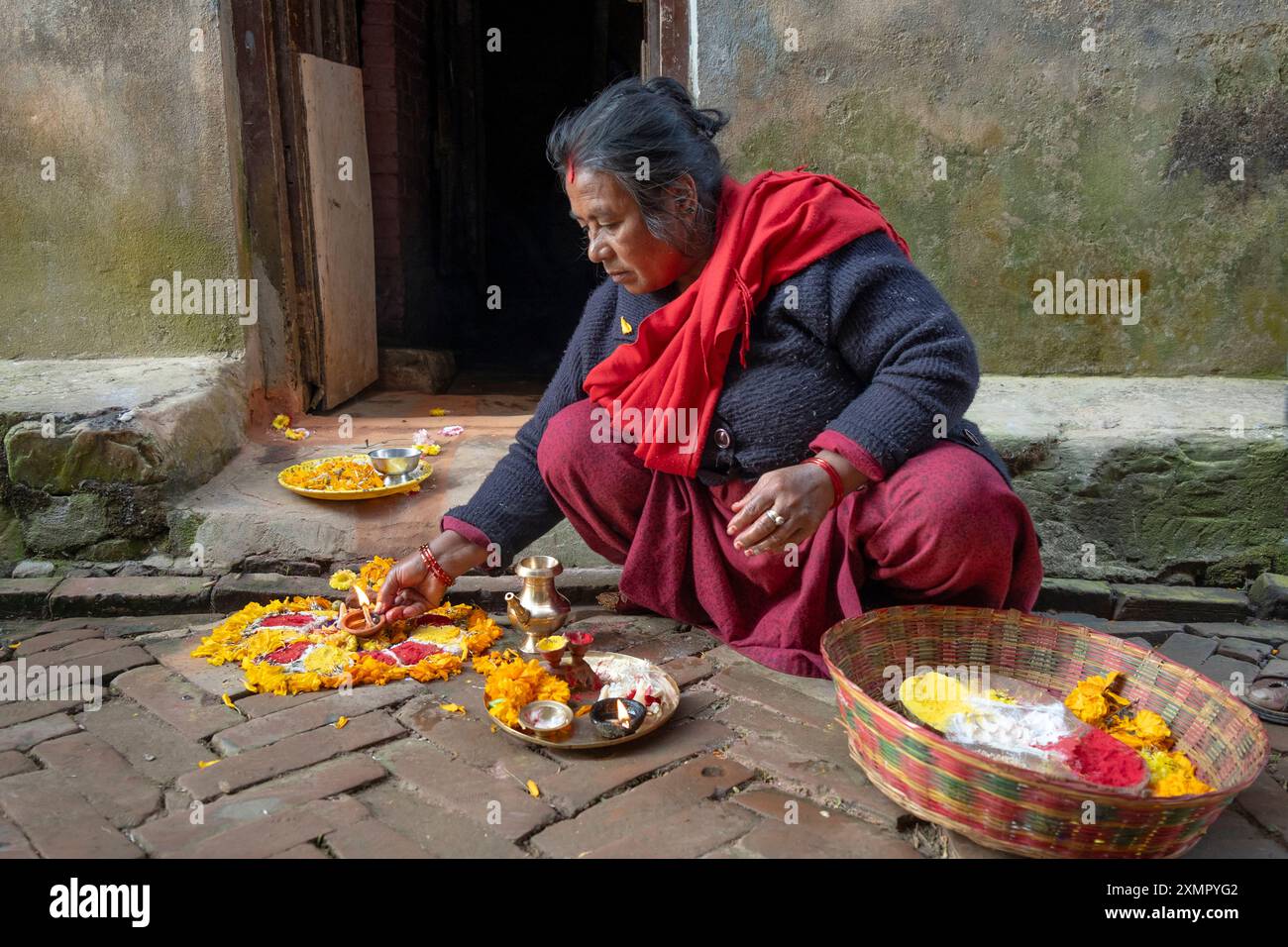 Frau bietet Puja mit Obst und Blumen vor ihrem Haus während des Diwali Festival of Lights im November in Panauti Town, Kathmandu, Nepal Stockfoto