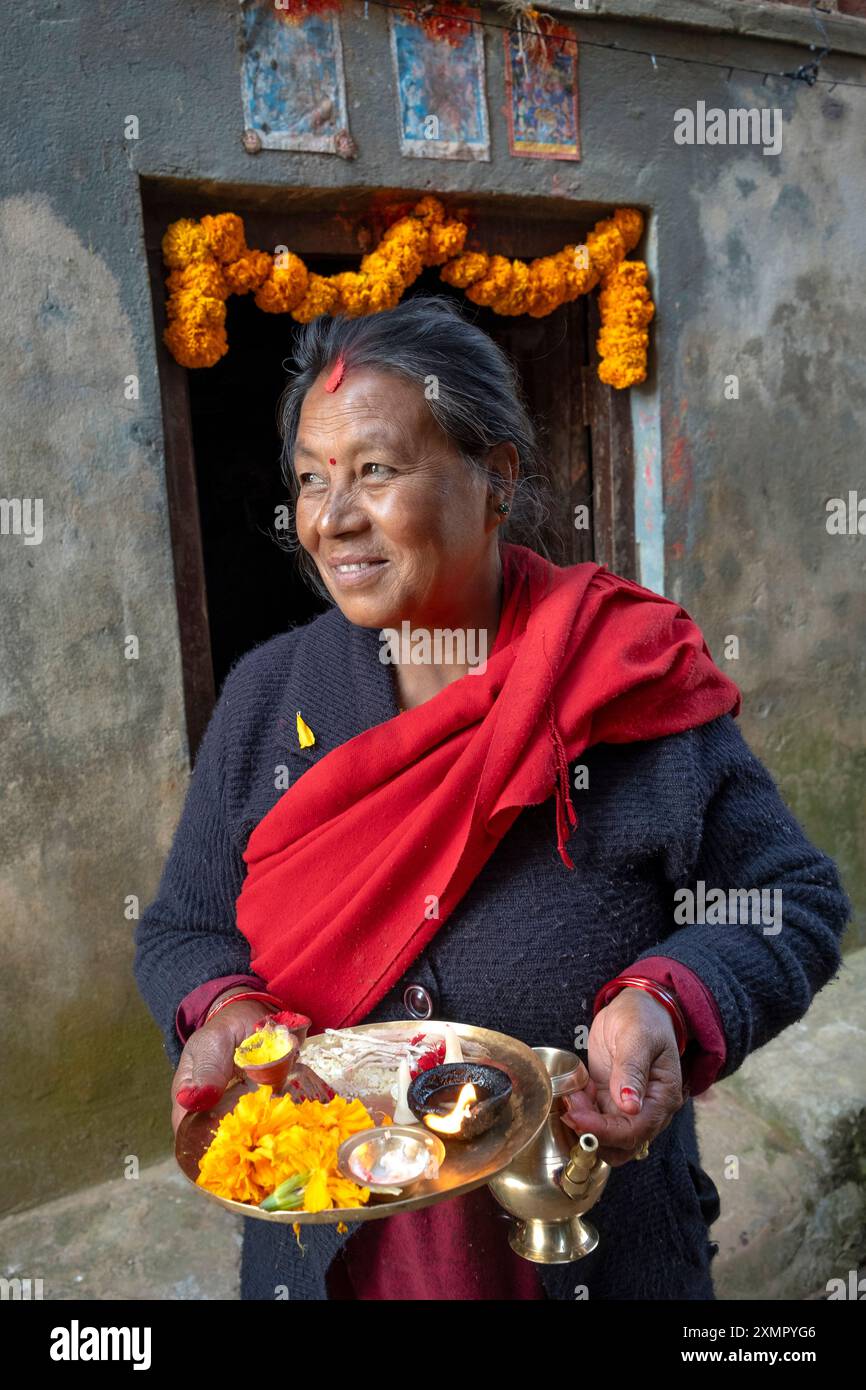 Frau bietet Puja mit Obst und Blumen vor ihrem Haus während des Diwali Festival of Lights im November in Panauti Town, Kathmandu, Nepal Stockfoto