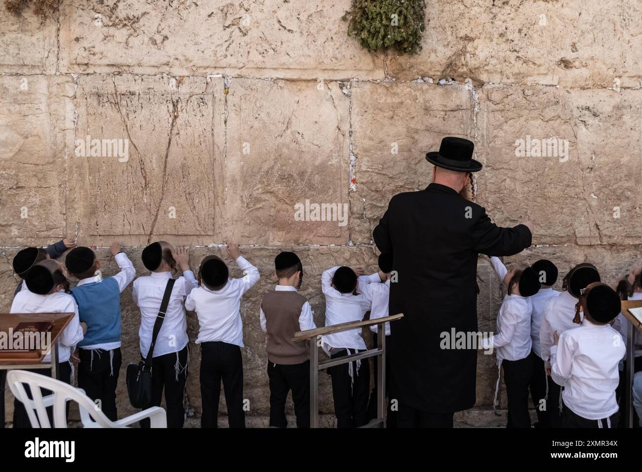 Jeshiva-Schüler und Lehrer beten an der Westmauer Männer Seite der Westmauer, auch bekannt als Klagemauer im Westen und Al-Buraq-Mauer im Islam, ist ein Pilgerziel für jüdische Gläubige. Es befindet sich in der Altstadt von Jerusalem und ist ein Teil der Stützmauer des Tempelbergs. Eine Metallwand teilte das Gebiet in zwei Teile auf: Männer auf der linken und Frauen auf der rechten Seite. Den ganzen Tag über besuchen jüdische Gläubige die Stätte, um zu beten, die heiligen Bücher der Thora zu lesen und Papiernotizen in den Rissen der Mauer zu hinterlassen. Das ganze Gebiet wird von israelischen Soldaten überwacht. (Foto: Matteo Placucci/SO Stockfoto