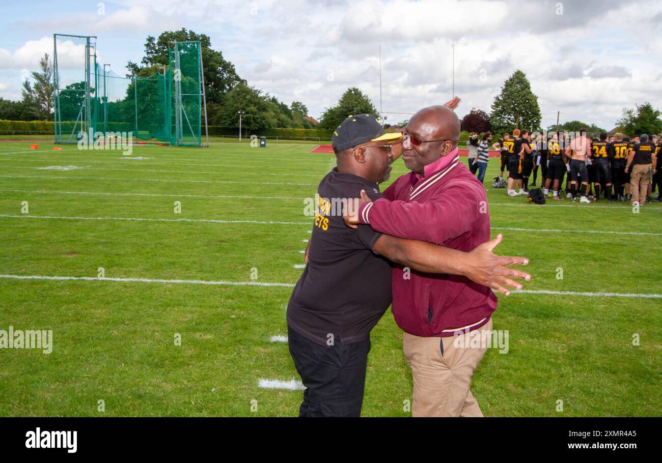 Nach einem sportlichen American Football zwischen den Ipswich Cardinals und den Besuchern der London Hornets umarmen sich die beiden Cheftrainer freundlich. Stockfoto