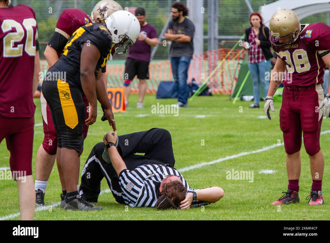 Bei einem American Football-Spiel in Ipswich UK ist ein Schiedsrichter umgefallen, nachdem eine große Person unbeabsichtigt auf den Fuß des Beamten gestanden hat, ein bisschen lustig:) Stockfoto