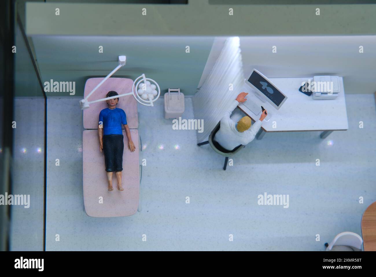 Patient liegt auf dem Untersuchungstisch neben dem am Computer arbeitenden Arzt. Übersichtssicht der ärztlichen Sprechstunde in der Klinik. Gesundheit und Diagnose Conce Stockfoto