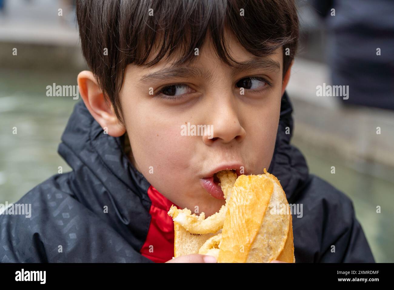 Junge beißen traditionelles Tintenfisch-Sandwich im Freien auf dem Major Square in der Innenstadt von Madrid in San Isidro Stockfoto