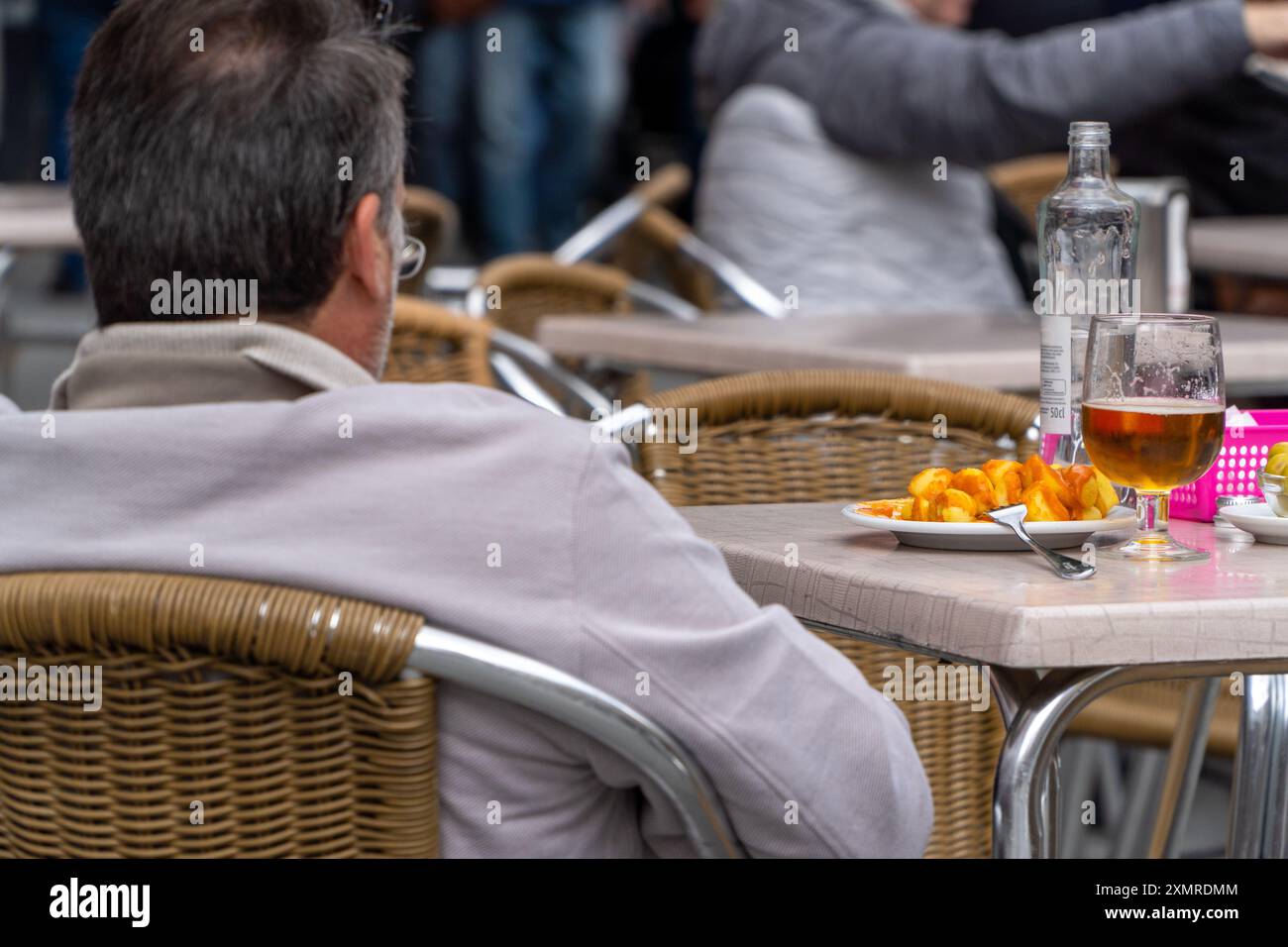 Männer essen spanische Tapas mit tapferen Kartoffeln auf der Bar-Terrasse auf dem traditionellen Aperitif Stockfoto