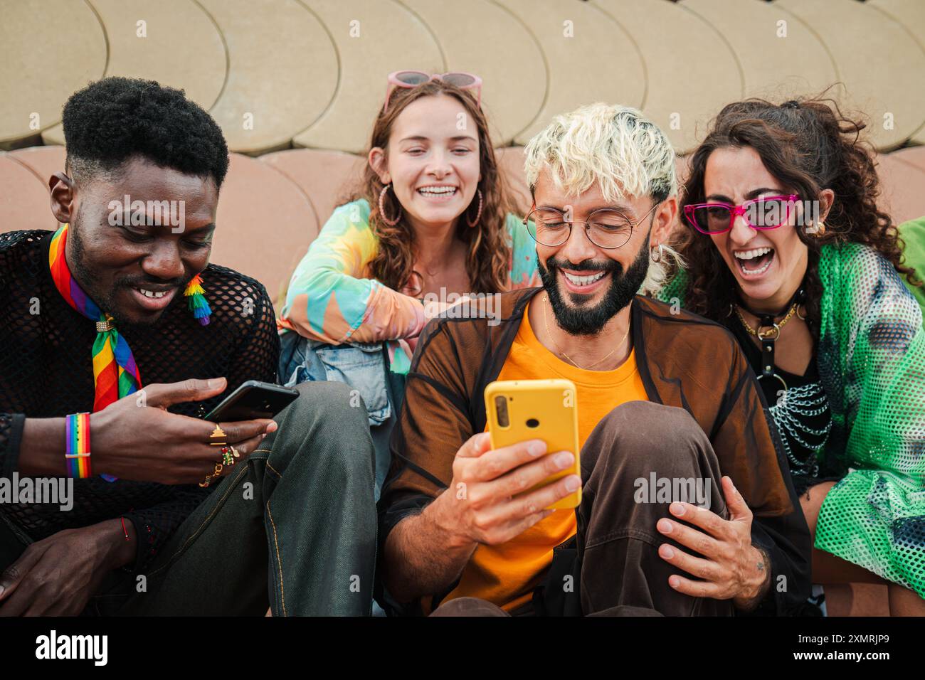 Junge, glückliche Menschen mit mehreren Rassen, die Spaß haben, während sie ein Mobiltelefon benutzen, um im Internet zu surfen und Fotos in sozialen Medien zu teilen. Eine Gruppe Frien Stockfoto