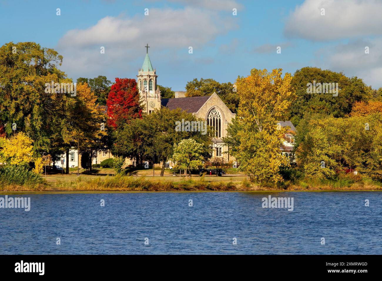 Herbstszene mit Blick über den Lake of the Isles in Richtung der 1925 Lake of the Isles Lutheran Church in Minneapolis, Minnesota. Die Kirche war designe Stockfoto