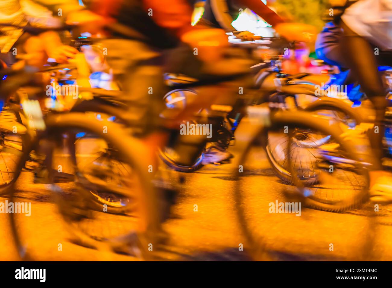 Verschwommene Bewegung von Radfahrern bei Nacht, lebendige Energie, bunte Lichter, dynamische Bewegung der belebten Straßenszene Stockfoto