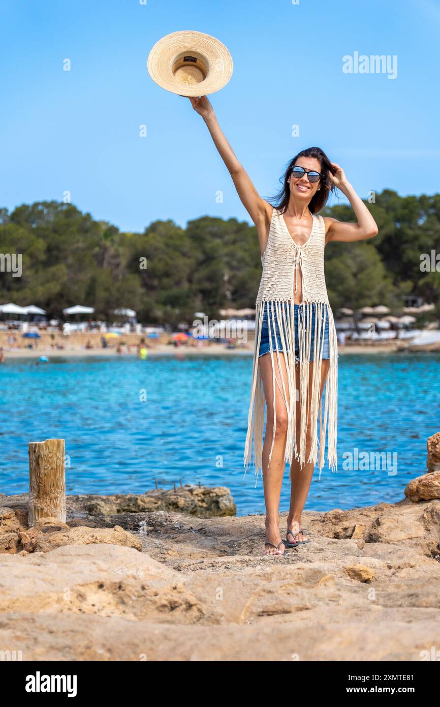 Junge Frau in einem Hemd mit Hutfräsen und Denim-Shorts im Cala Bassa Ibiza Stockfoto