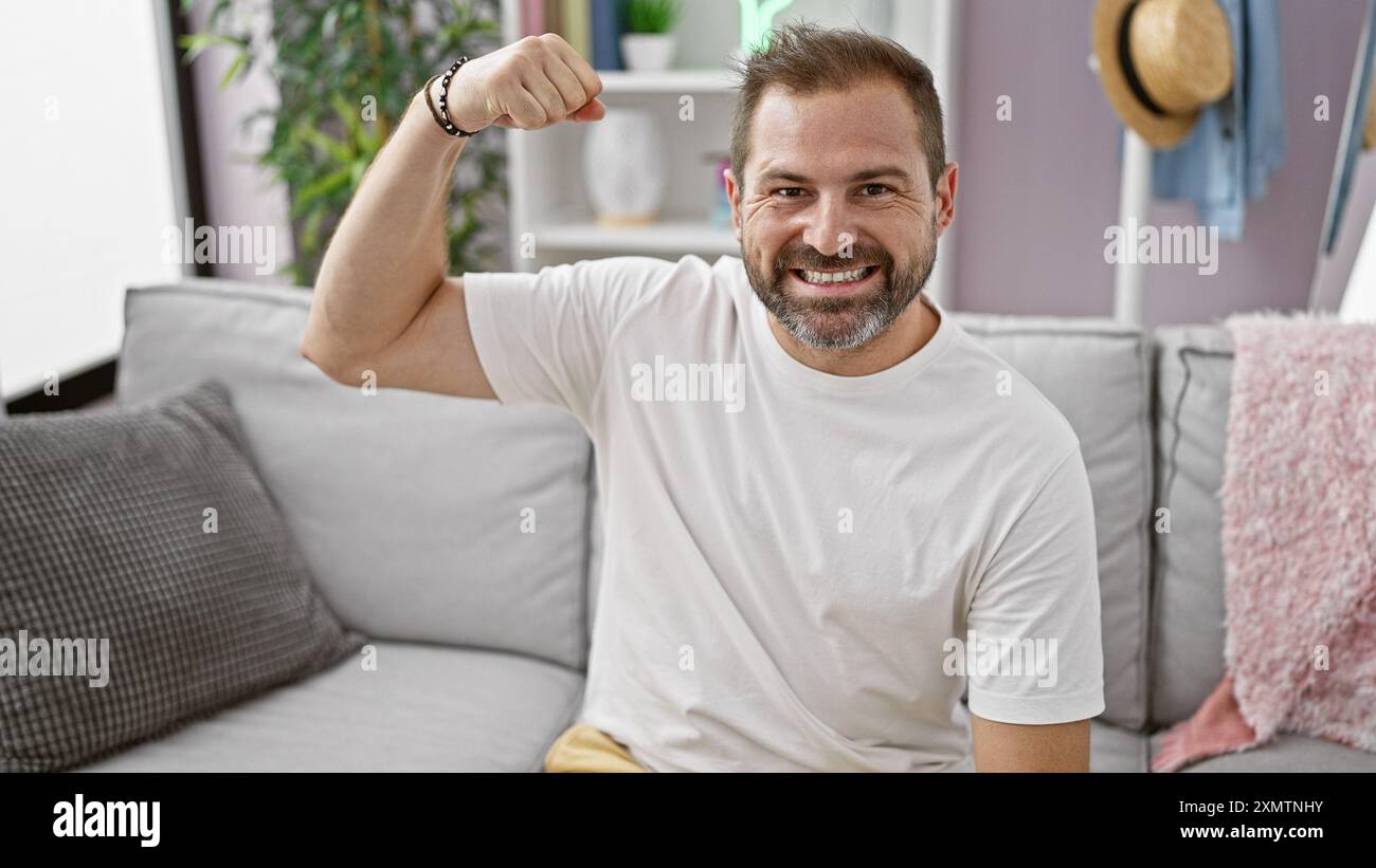 Lächelnder Mann mittleren Alters mit grauem, flexiblem Arm in einem modernen Wohnzimmer. Stockfoto