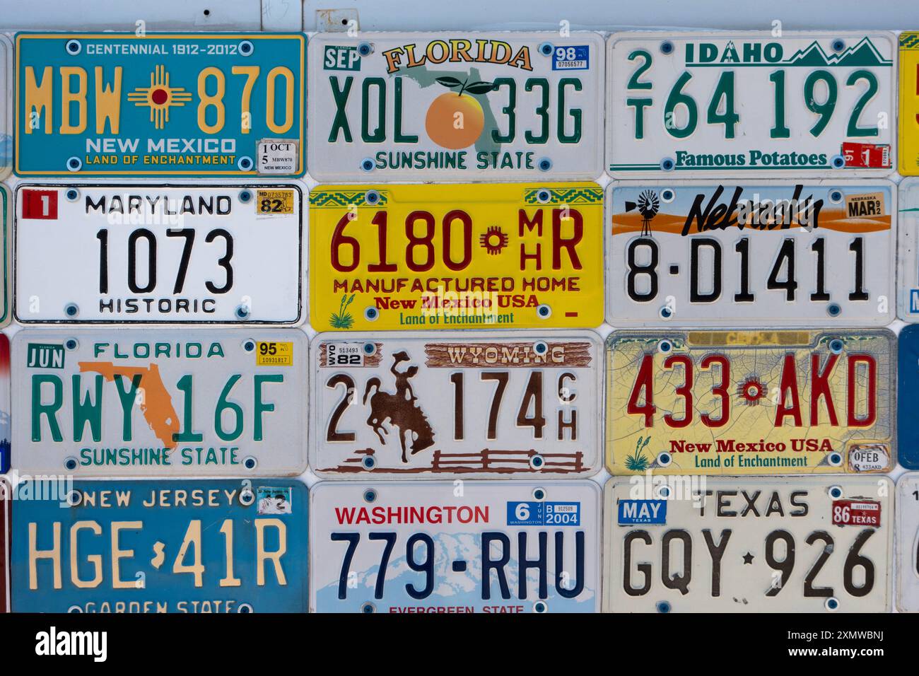 Sammlung alter amerikanischer Nummernschilder, die an eine Wand genagelt wurden, aus verschiedenen US-bundesstaaten Stockfoto