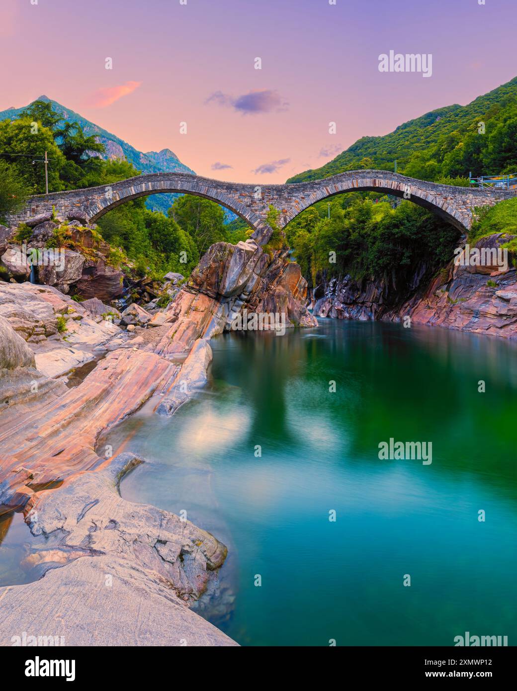 Ein vertikales 4:5 Bild von einem Sommersonnenaufgang an der Brücke Ponte dei Salti. Die alte Steinbrücke (auch Ponte Romano genannt) überspannt den Verzasca Fluss i Stockfoto