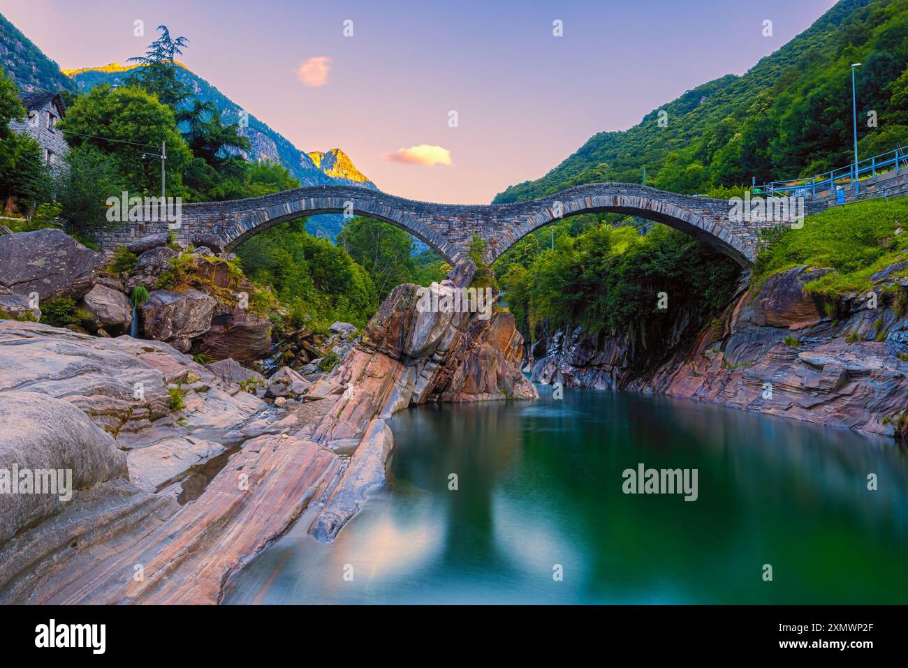 Ein Sommersonnenaufgang an der beleuchteten Brücke Ponte dei Salti. Die Brücke (auch „Ponte Romano“ genannt) überspannt den Verzasca Fluss in Lavertezzo und ist eine Tante Stockfoto