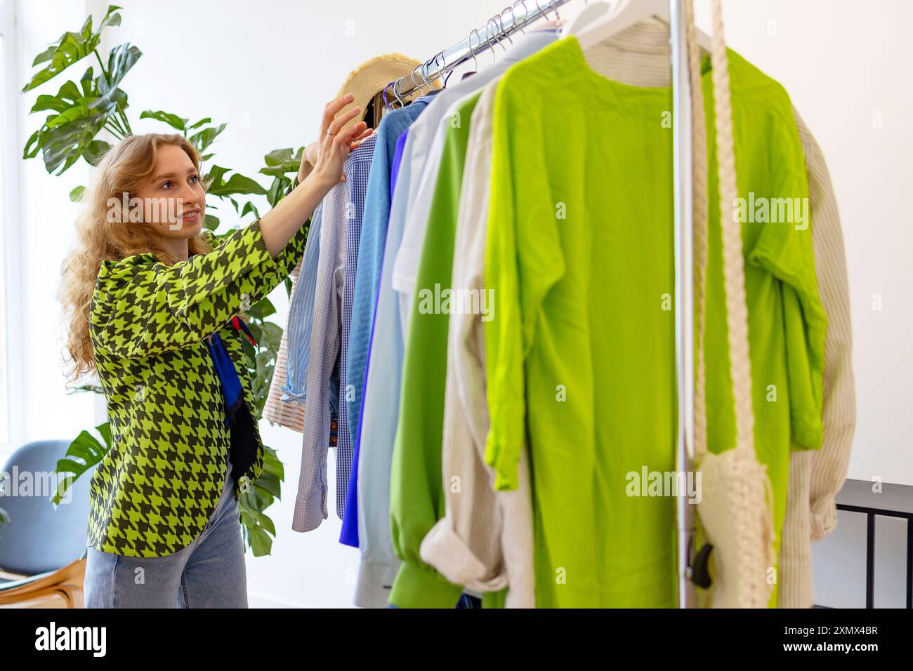 Second-Hand-Laden, spart Geld und Familienbudget, junge Studentin auf der Swapparty probiert Kleidung, Taschen, Schuhe und Accessoires an, wechselt Kleidung mit Stockfoto