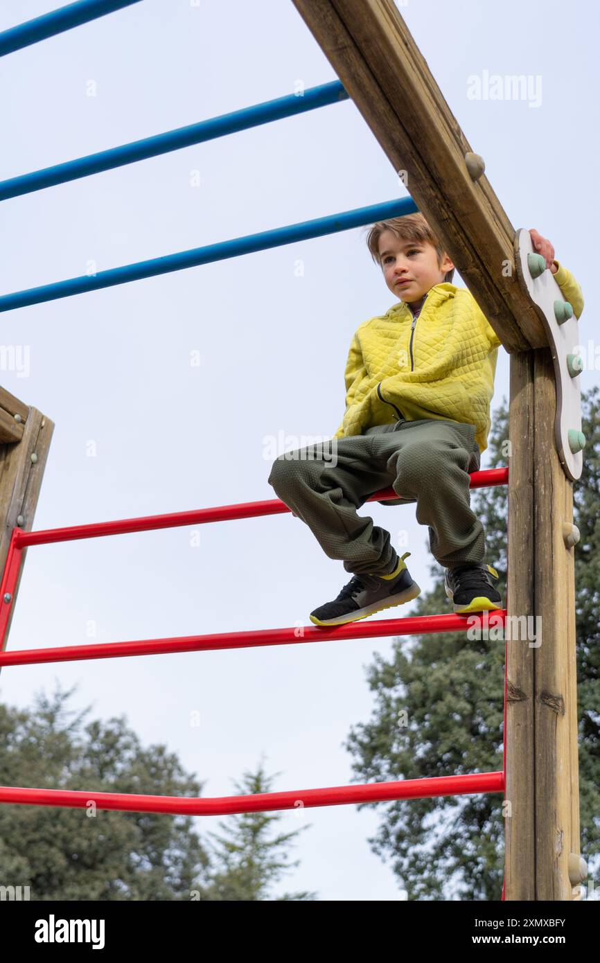 Kaukasischer Junge, der auf einem Spielplatz sitzt Stockfoto