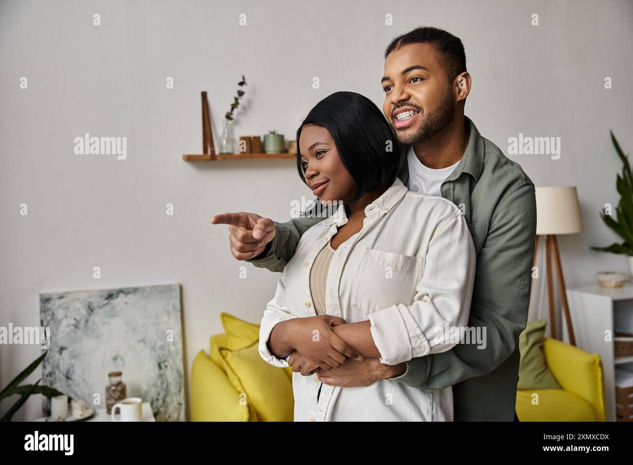 Ein afroamerikanisches Paar umarmt sich und zeigt auf gemeinsame Träume und eine hoffnungsvolle Zukunft. Stockfoto