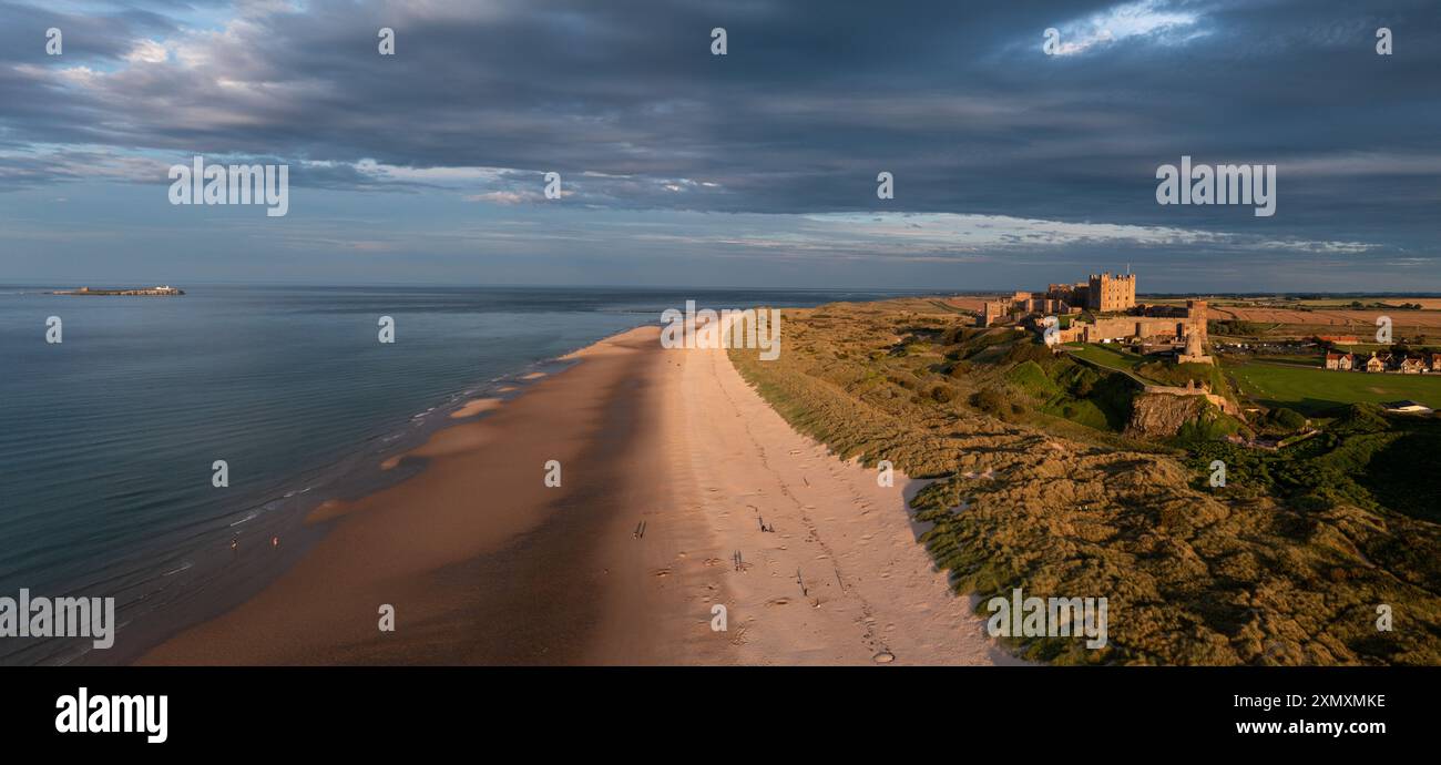 Bamburgh Castle mit Inner Farne, die sich in der Abendsonne an der Küste von Northumberland sonnen. Stockfoto