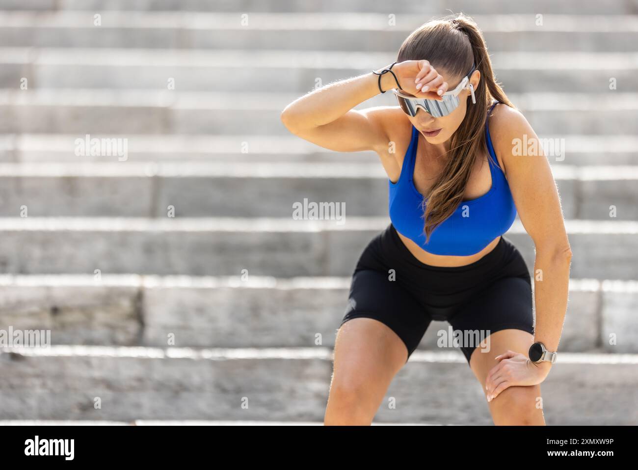 Eine müde junge Läuferin ruht sich nach einem anstrengenden Lauf die Treppe hinauf. Stockfoto