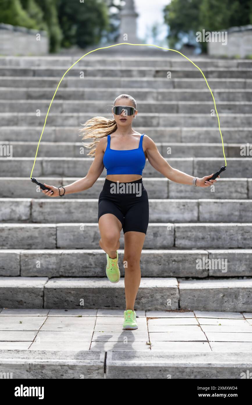 Außenaufnahme einer Frau in Sportbekleidung, die draußen in einem Park mit Seilspringen trainiert. Fitnesstraining-Frau mit Sprungseil in einem Park. Stockfoto