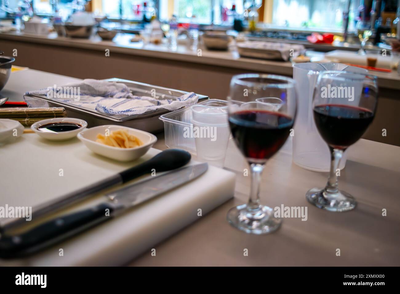 Ein Blick auf eine Sushi-Werkstattküche mit einem Glas Wein, die die Mischung aus kulinarischer Zubereitung mit einem eleganten Hauch Wein hervorhebt Stockfoto