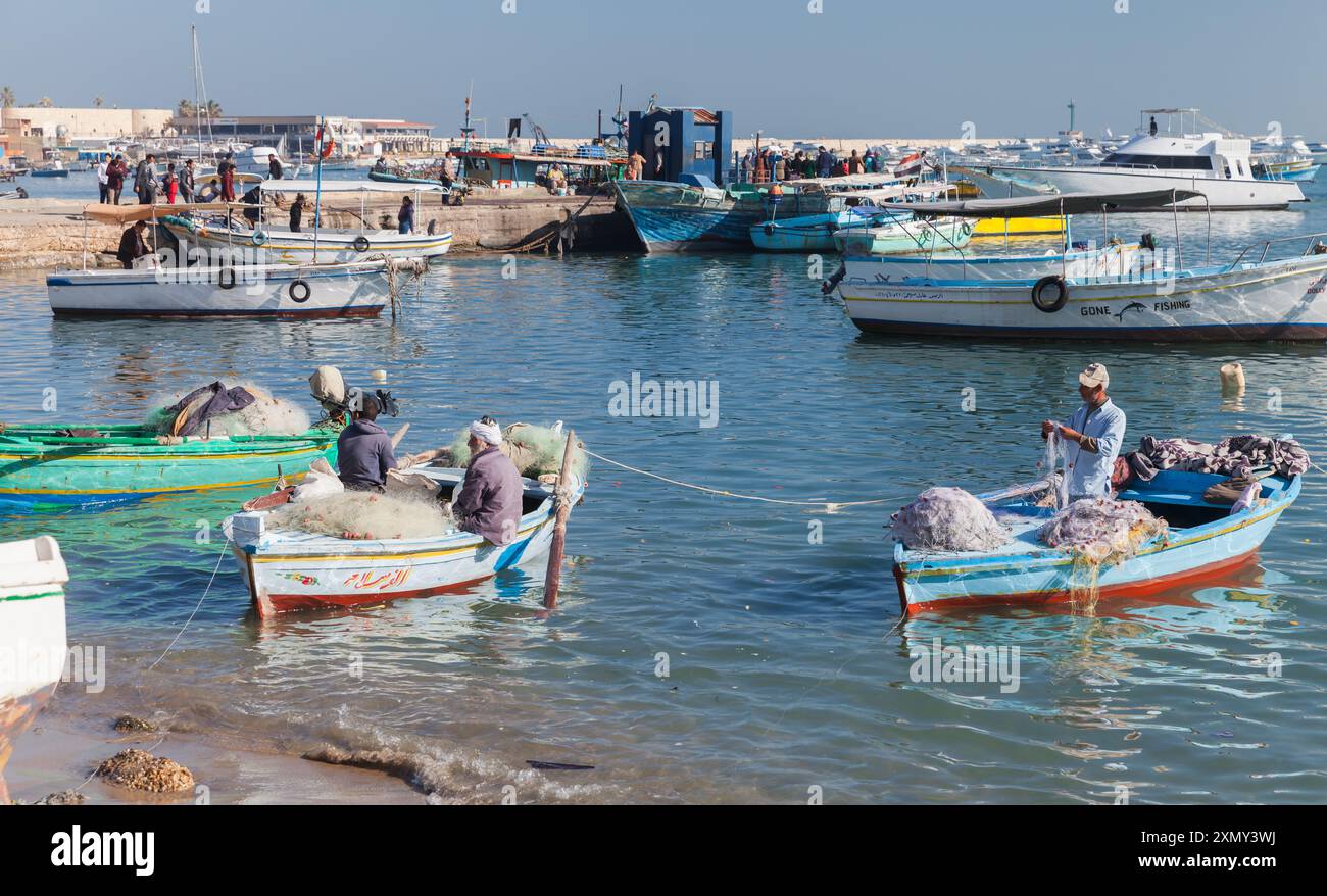 Alexandria, Ägypten - 14. Dezember 2018: Fischer sitzen in kleinen Holzbooten. Blick auf die Küste des alten Fischerhafens von Alexandria Stockfoto