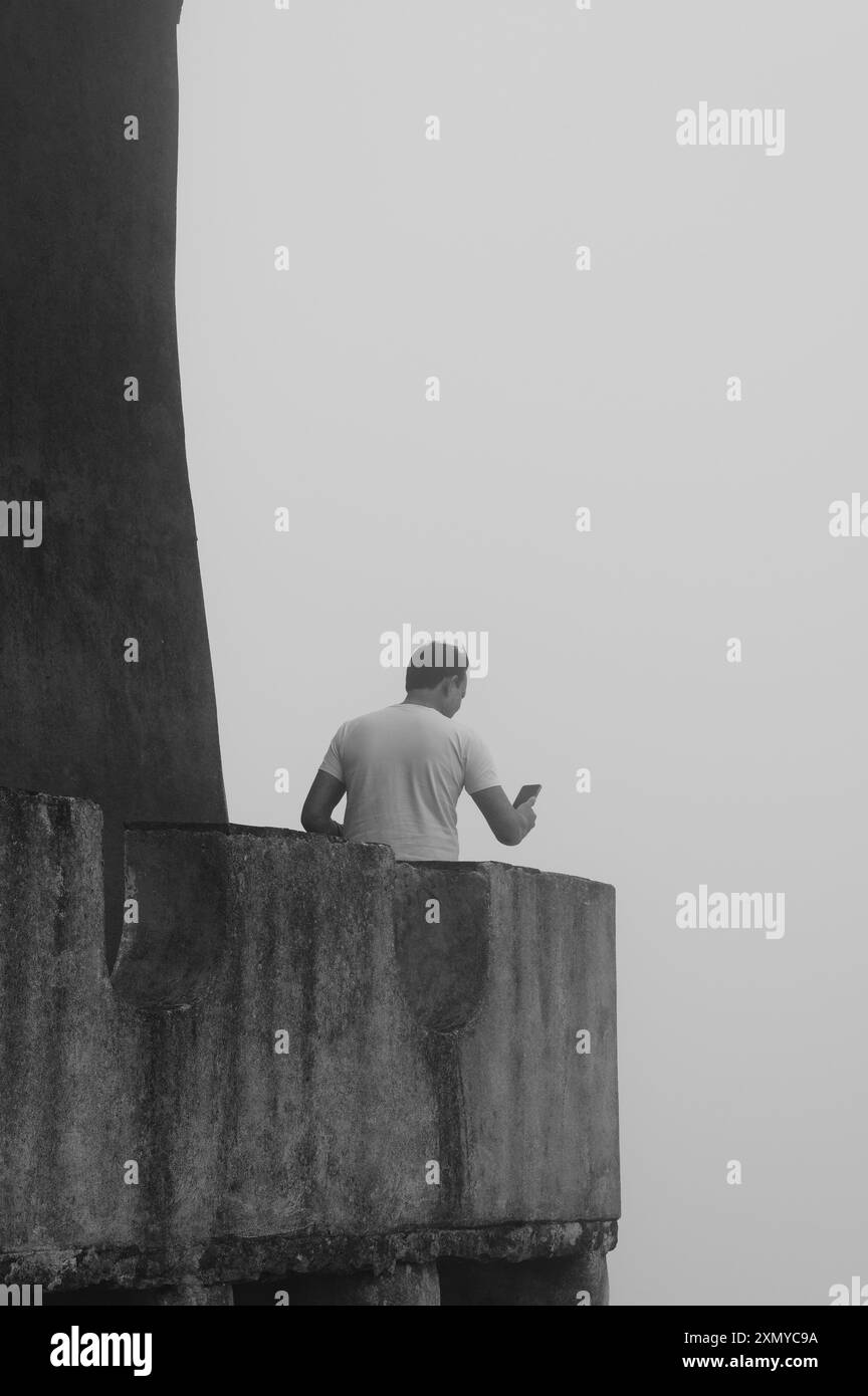 Eine Einzelfigur blickt in den Nebel, während sie ein Foto von einem Turm des Pena Palace macht Stockfoto