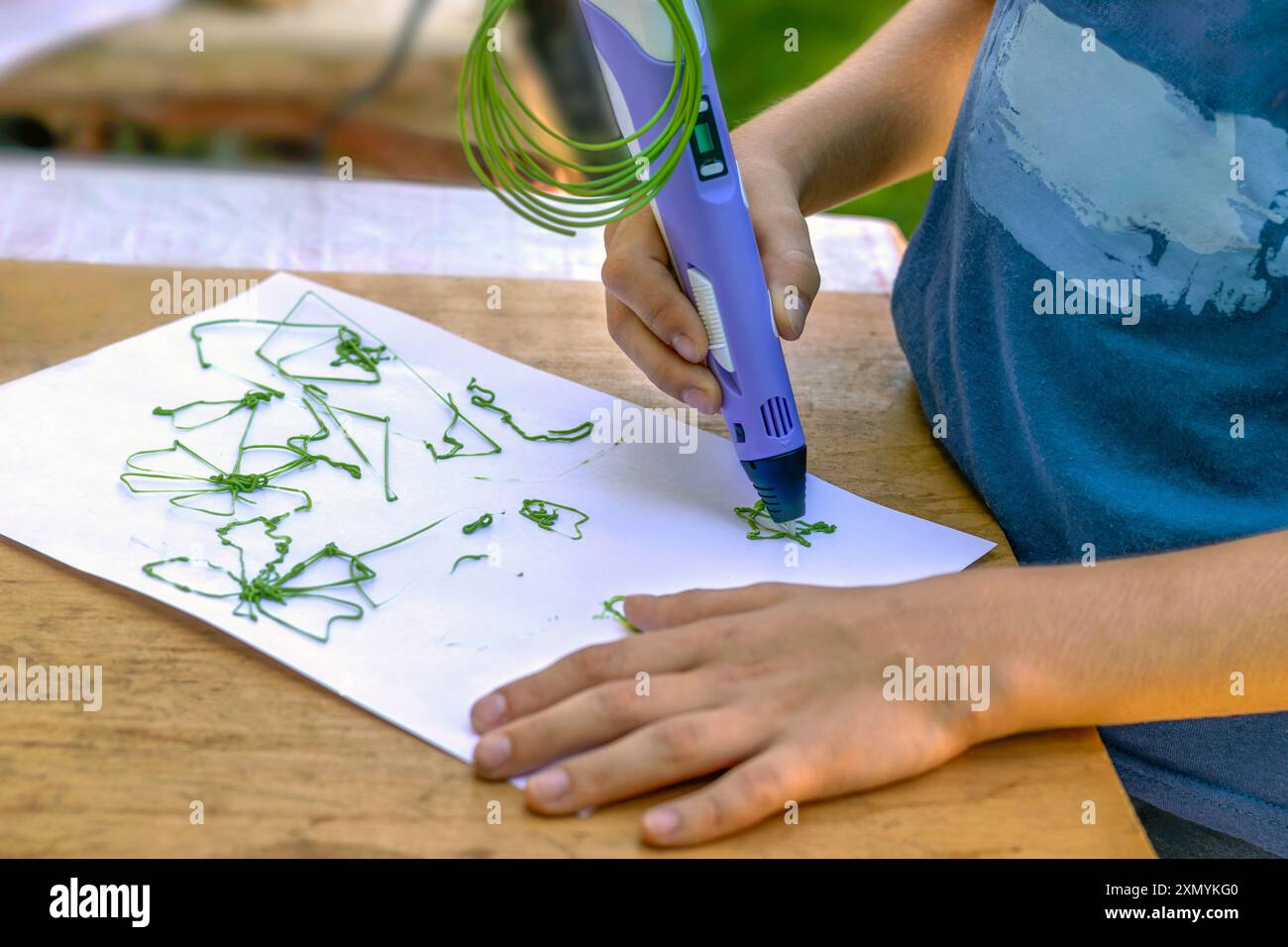 Junge zeichnet Figuren mit 3D-Stift auf Papier. Nahaufnahme. Stockfoto