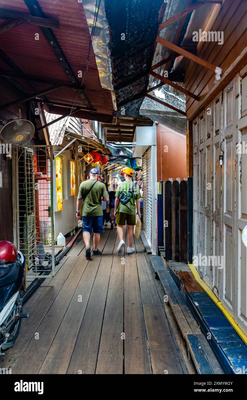 Ein paar Touristen, die durch eine Gasse am Chew Jetty, George Town, Penang, Malaysia laufen Stockfoto