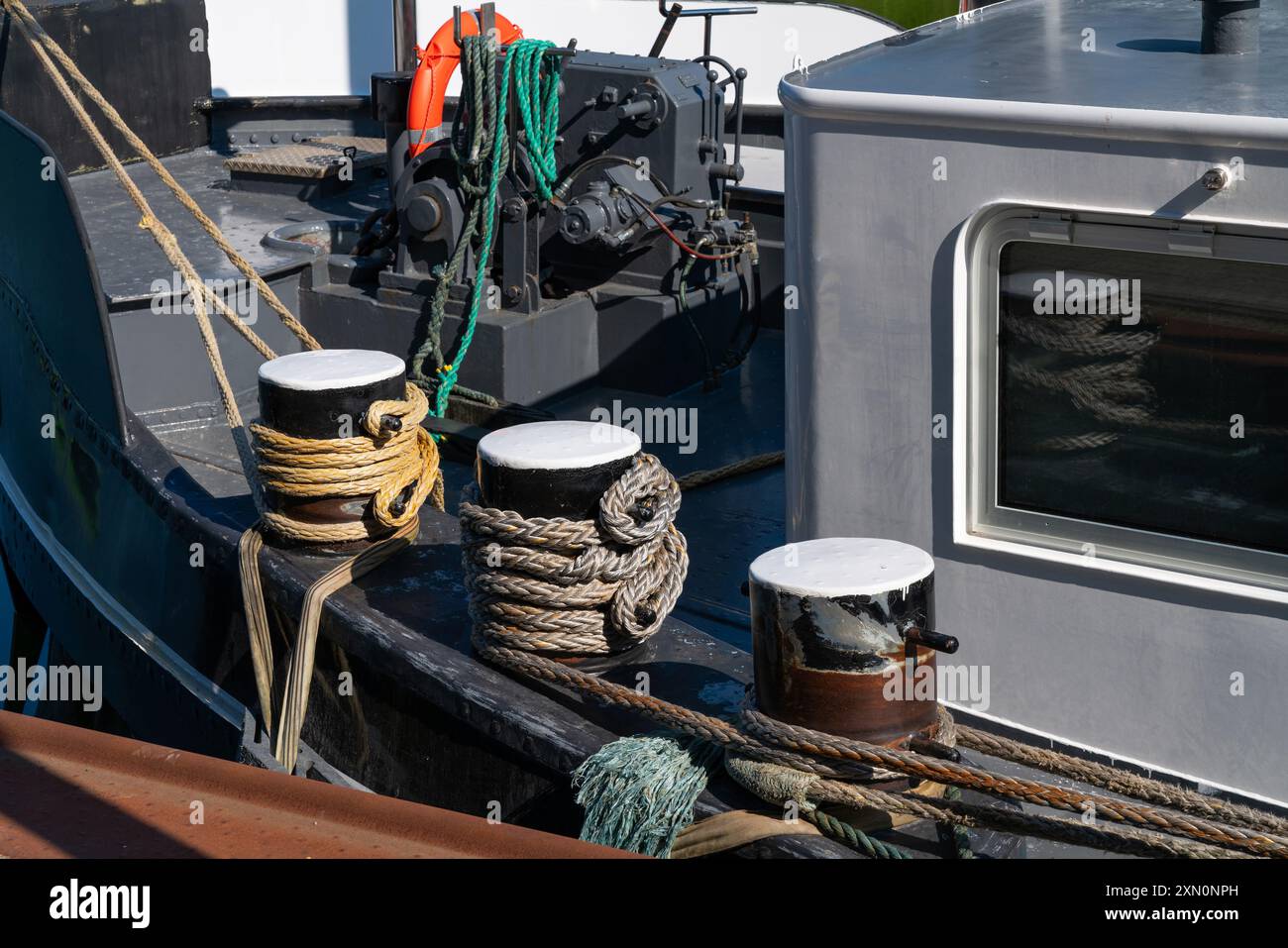 Festmacherleinen und -Stollen sind auf einem Fischerboot befestigt und zeigen die komplizierten Knotenarbeiten und die Ausrüstung, die zum Andocken im Hafen verwendet wird. Stockfoto