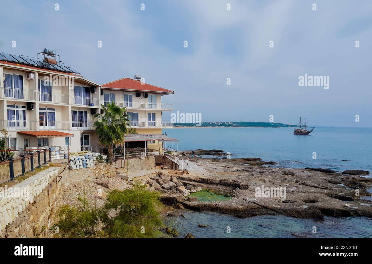 Side, Türkei, November 2019: Segelboot mit abgesenktem Mittelmeer segelt entlang einer Küste mit Apartmenthotel. Stockfoto