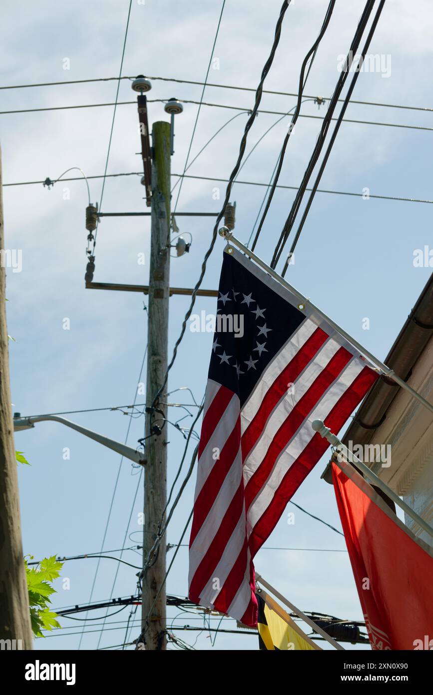 USA-Flagge mit einem Chaos an öffentlichen Stromleitungen dahinter. Antiquierte Infrastruktur. Stockfoto