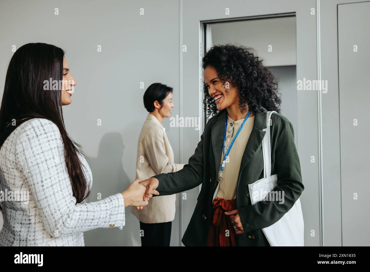 Zwei Geschäftsfrauen tauschen bei einer Firmenveranstaltung einen freundlichen Abschiedshandschlag aus und drücken Dankbarkeit und Kameradschaft aus. Stockfoto