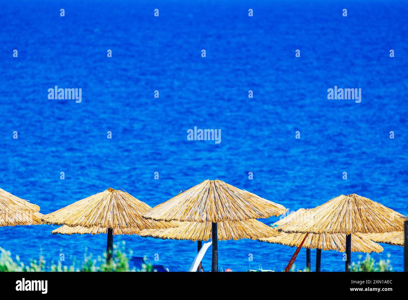 Strohschirme vor hellblauem Meeresgrund. Griechenland. Stockfoto