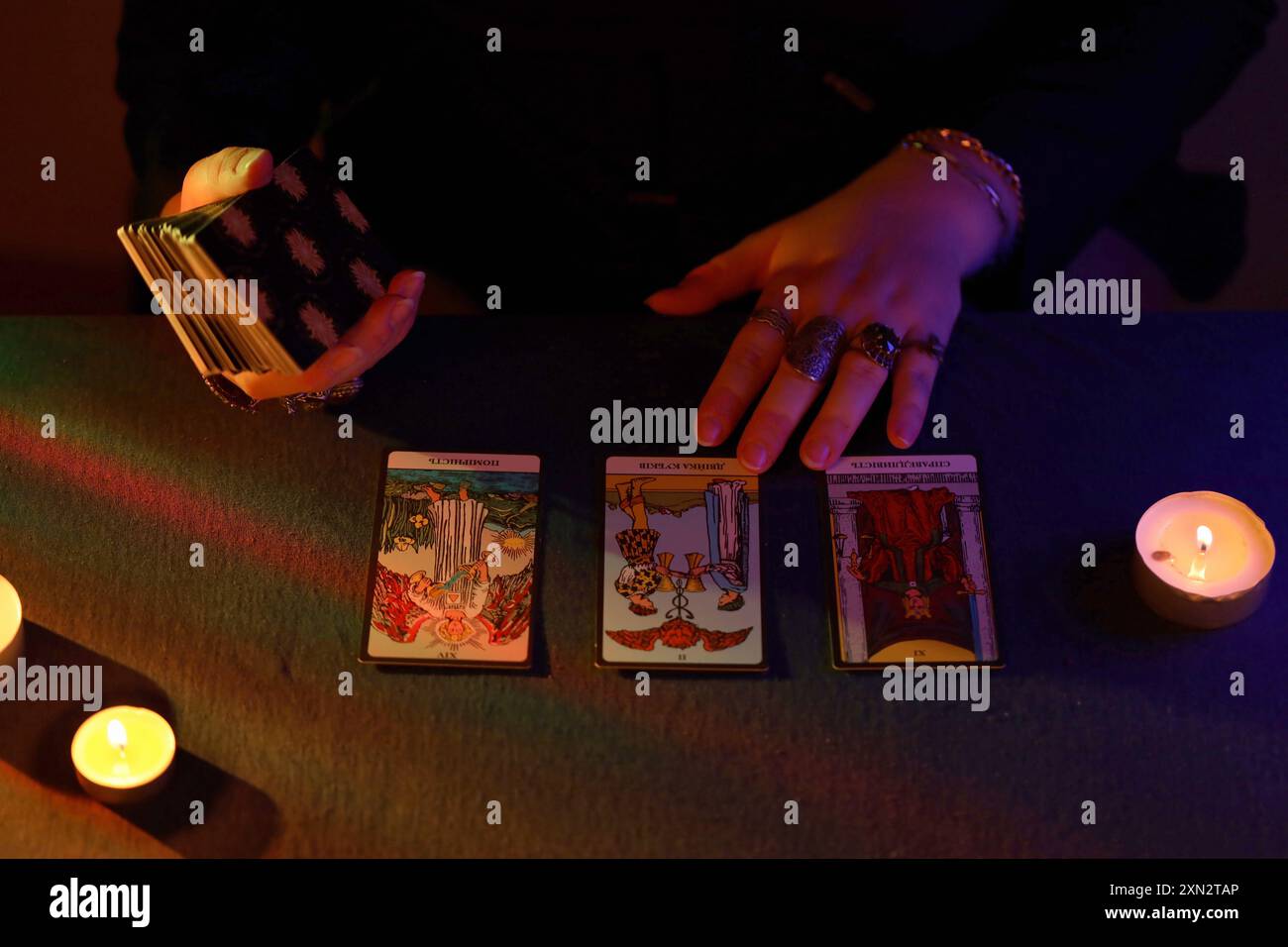 KIEW, UKRAINE - 10. JULI 2024 Tarotleser wählt Tarotkarten aus. Kerzenlicht im dunklen Raum. Tarot-Leser oder Wahrsager lesen und Prognosen aus nächster Nähe Stockfoto
