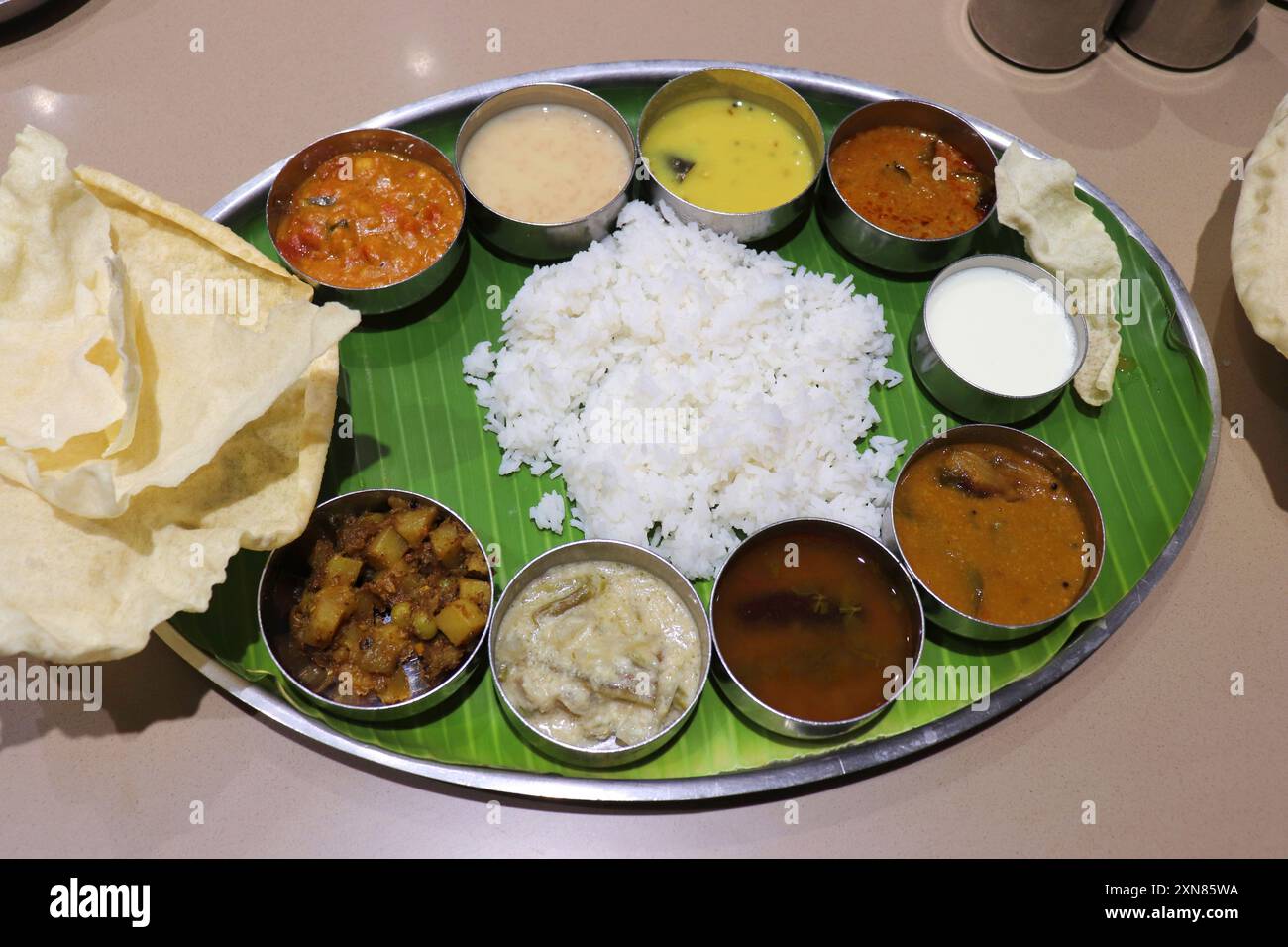 Ein südindischer Thali oder eine Mahlzeit besteht aus gedämpftem Reis, Sambar, Rasam, Gemüsecurrys, Avial, Kokos-Chutney, Gurken, Papadum, Quark oder Joghurt Stockfoto Ein südindischer Thali oder eine Mahlzeit besteht aus gedämpftem Reis, Sambar, Rasam, Gemüsecurrys, Avial, Kokos-Chutney, Gurken, Papadum, Quark oder Joghurt Stockfoto