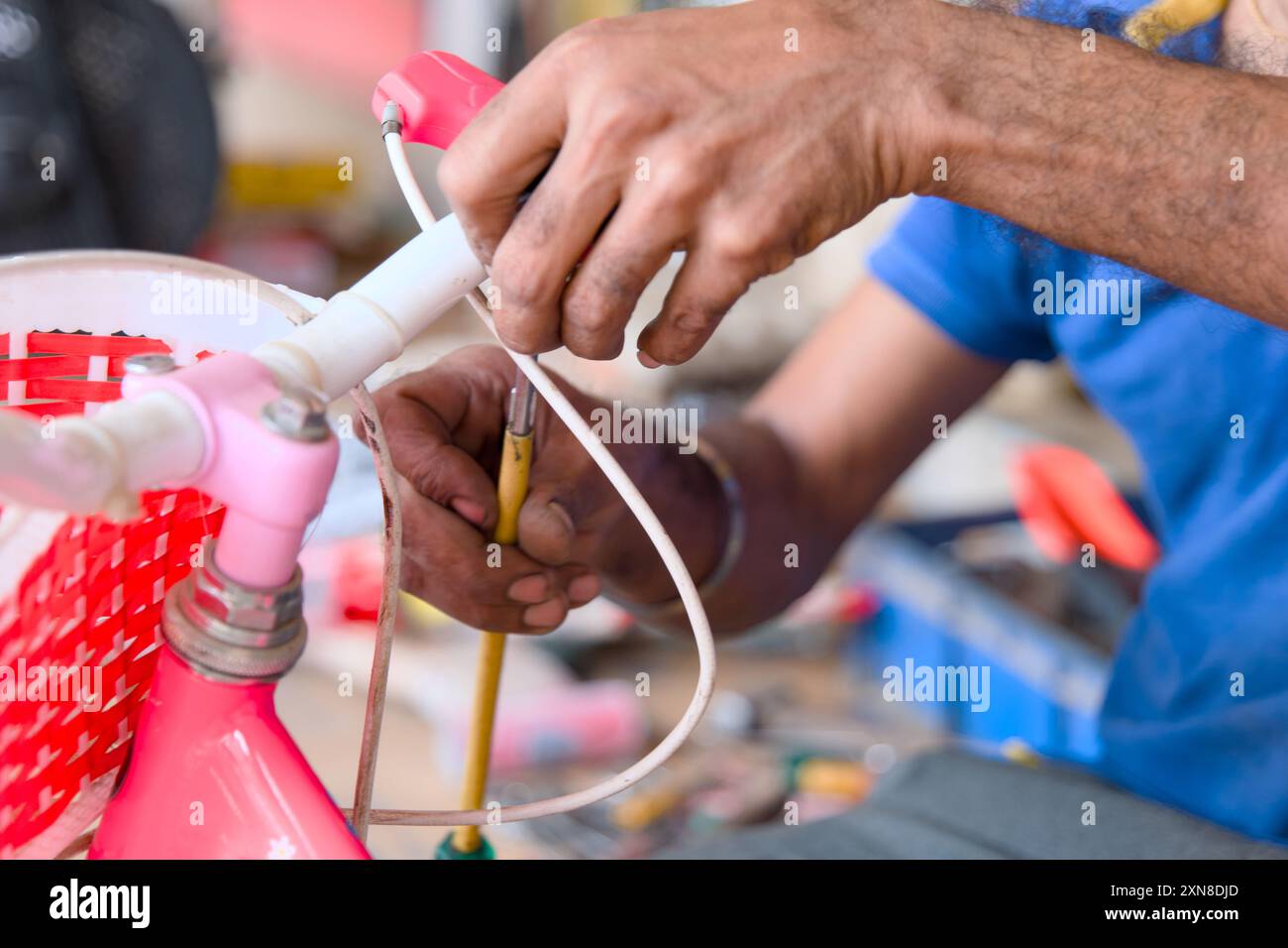 Geschickte Hände reparieren das pinkfarbene Kinderfahrrad sorgfältig und bringen dem Spielvergnügen wieder Freude Stockfoto