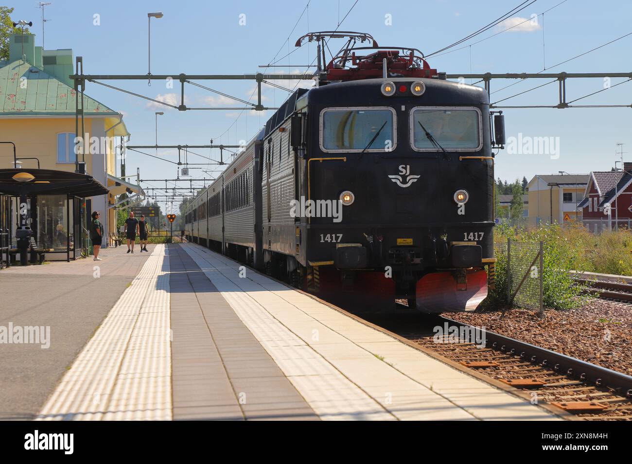 Hedemora, Schweden - 30. Juli 2024: SJ Intercity-Zug mit Elektrolokomotive der Baureihe RC6 1417 von Stockholm aus gezogen und erreicht den Bahnhof Hedemora. Stockfoto