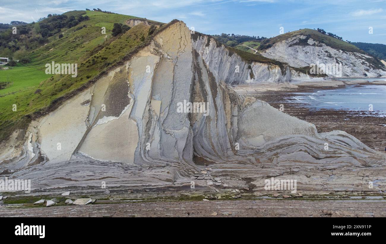 Ein Blick aus der Luft auf eine erodierte Klippe und längsschichtförmige Felsformationen am Ufer des Atlantischen Ozeans. Sakoneta Flysch, Deba, Gipuzkoa, Spanien. Stockfoto